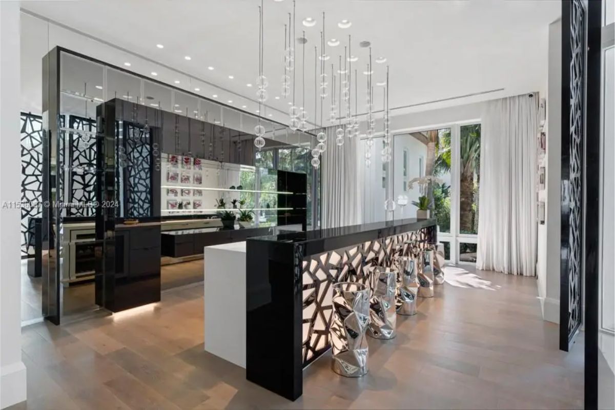 Stylish bar area featuring glossy black surfaces, mirrored walls, geometric bar stools, and an arrangement of hanging glass pendant lights. 