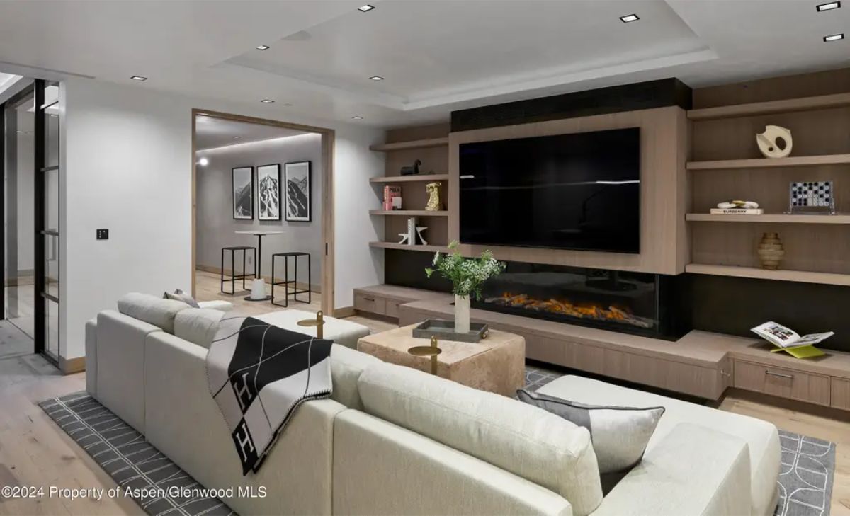 Chic entertainment area with a large TV, modern fireplace, and a warm wood-accented design. 