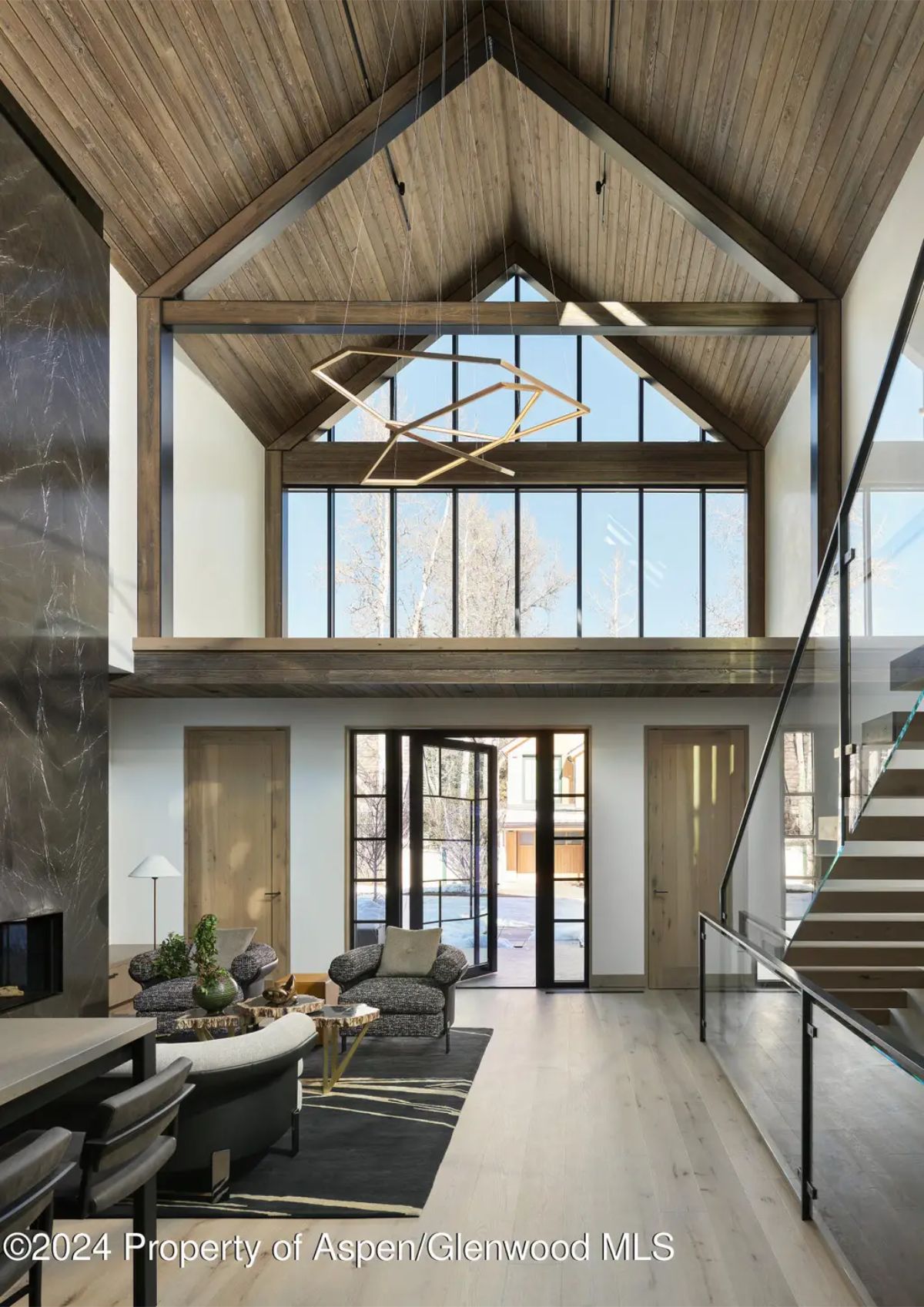 Grand entryway with vaulted wooden ceilings, large windows, and a striking geometric chandelier. 