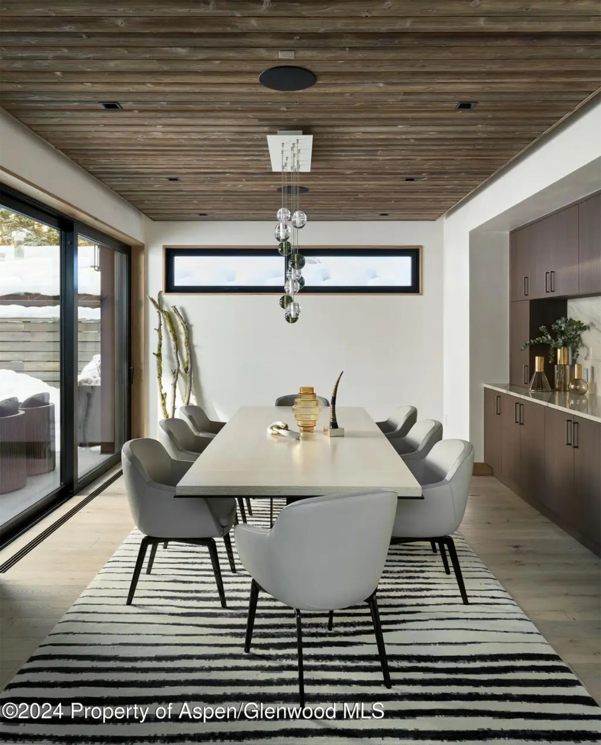 Sophisticated dining space with a contemporary chandelier, a sleek table, and a mix of natural textures. 