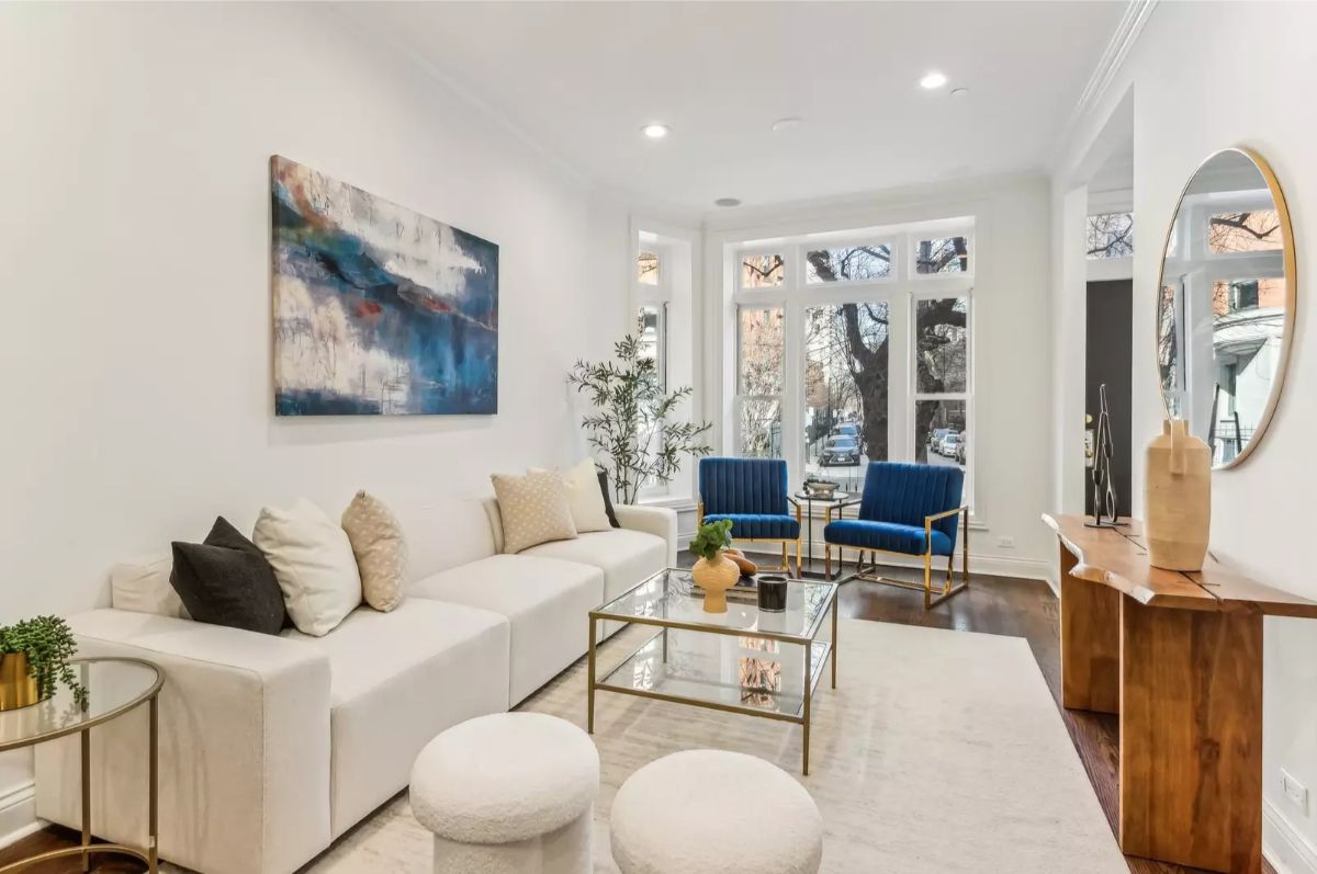 Neutral-toned furniture contrasts with blue accent chairs and abstract artwork on the wall.