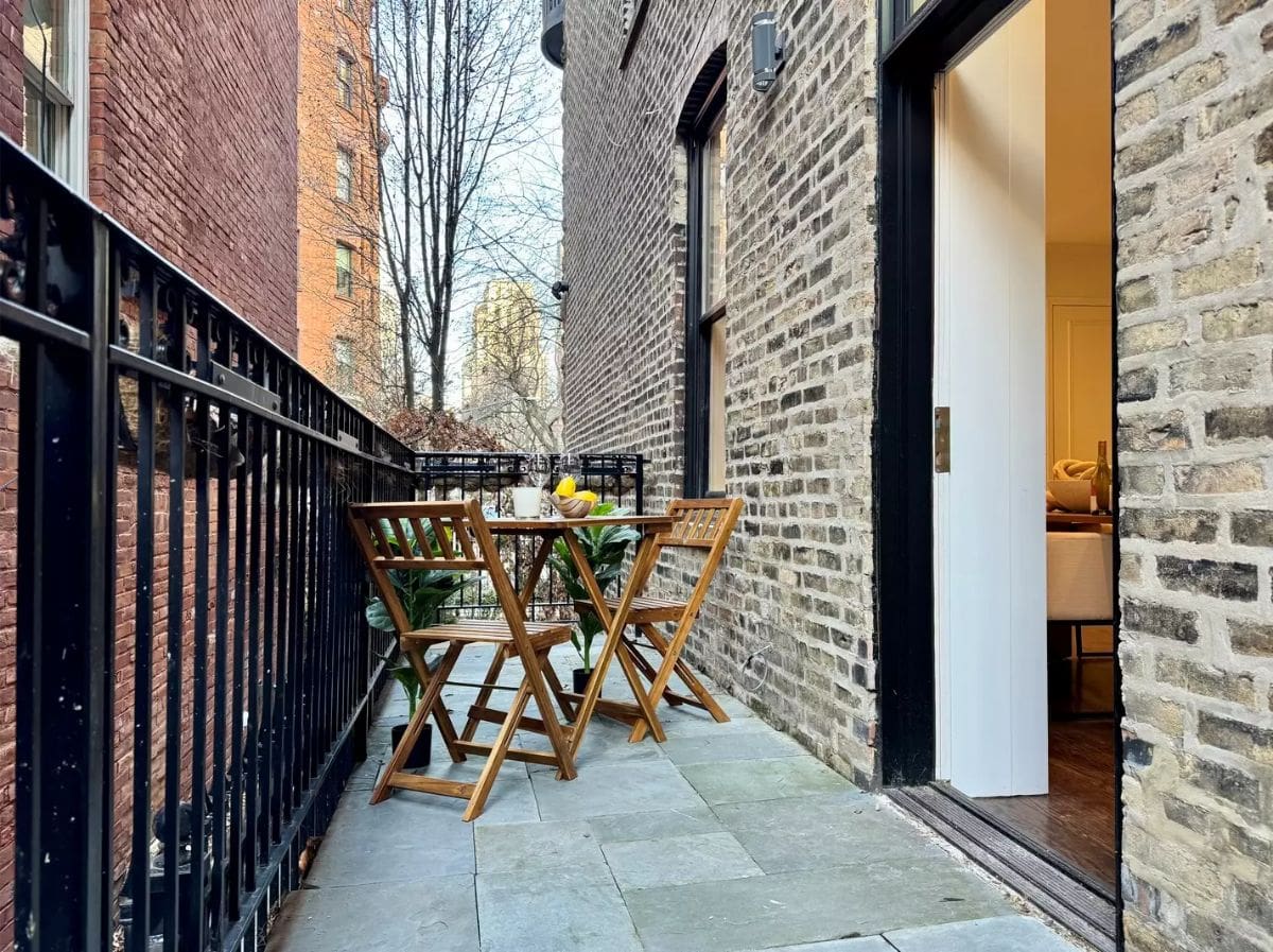 Brick walls enclose a small balcony with a black metal railing.