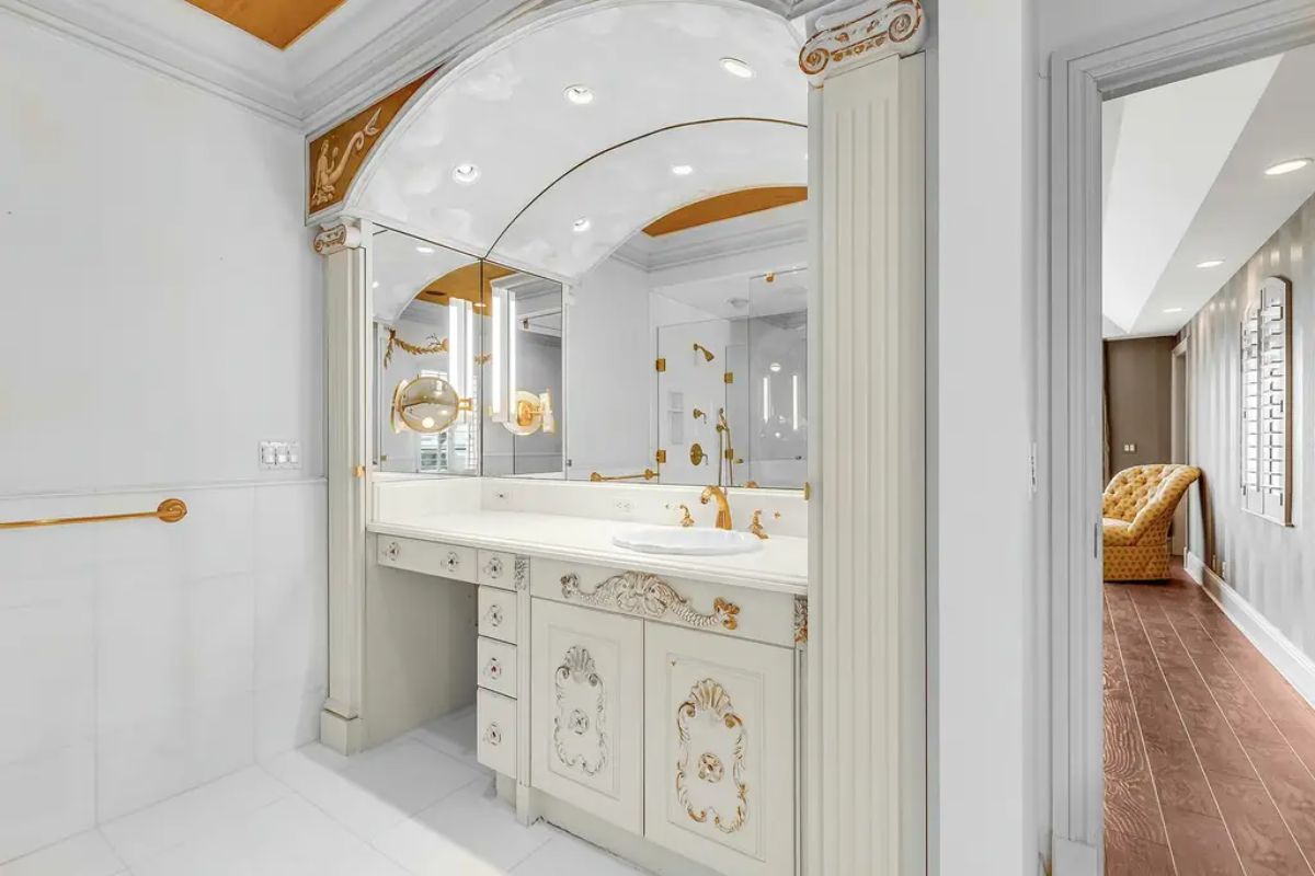 Elegant vanity area features intricate gold accents, large mirrors, and a decorative arched ceiling for a regal touch. 