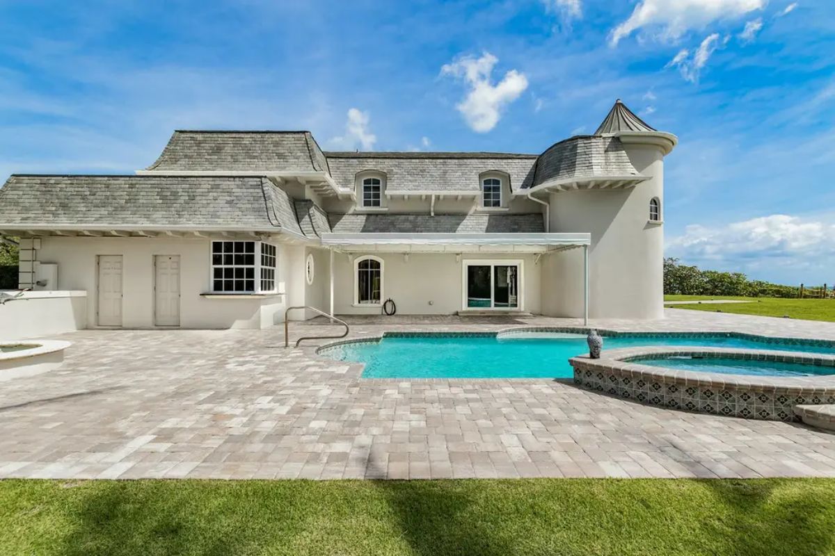 Sparkling outdoor pool is complemented by a spacious stone patio and a turret-like architectural feature on the house. 