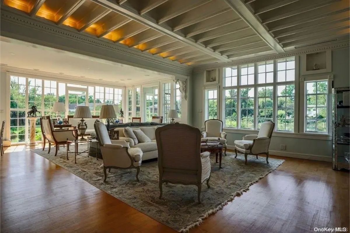 Spacious living area with a coffered ceiling and recessed lighting, offering a mix of traditional and modern furnishings.