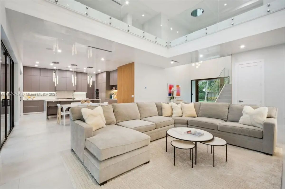 Living space with a plush L-shaped sofa, a marble coffee table, and an open connection to the kitchen and dining area. 