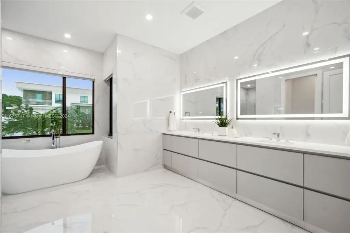 Spa-inspired bathroom featuring a freestanding tub, double vanity, and marble walls. 