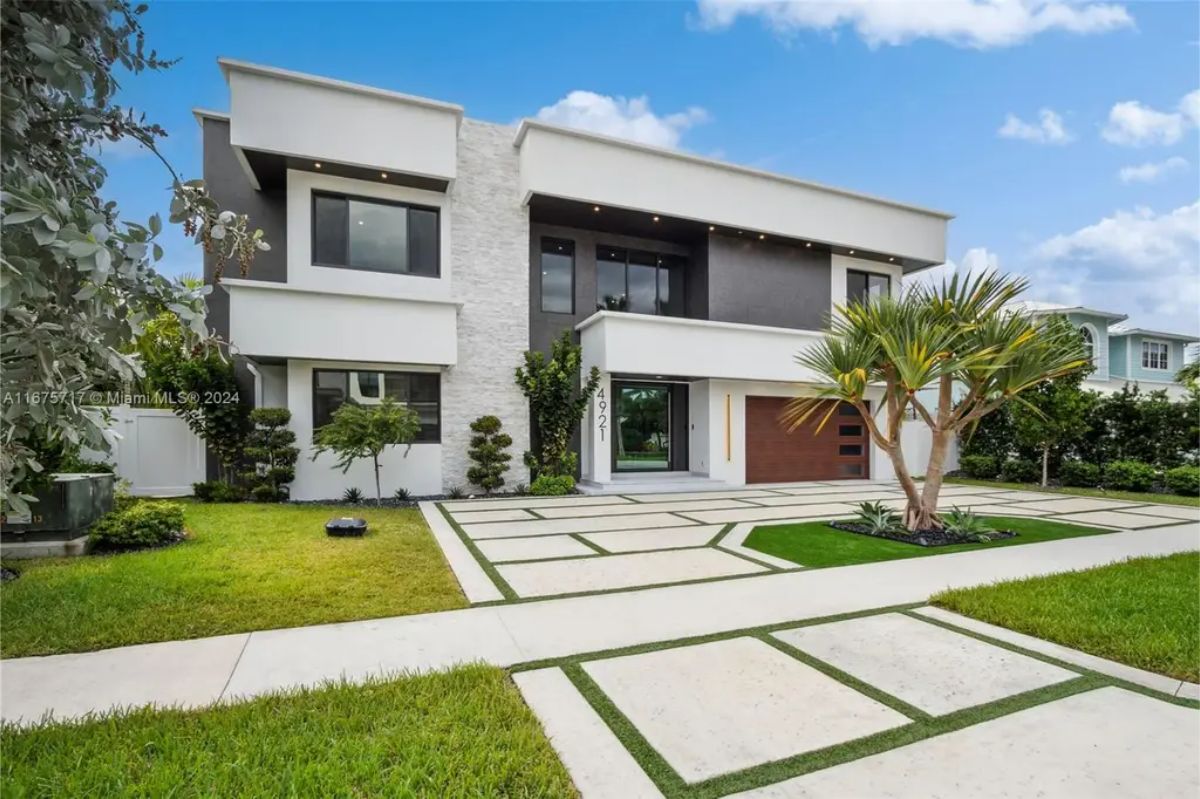 Contemporary two-story house with a white and dark exterior, a beautifully landscaped front yard, and a stylish driveway. 