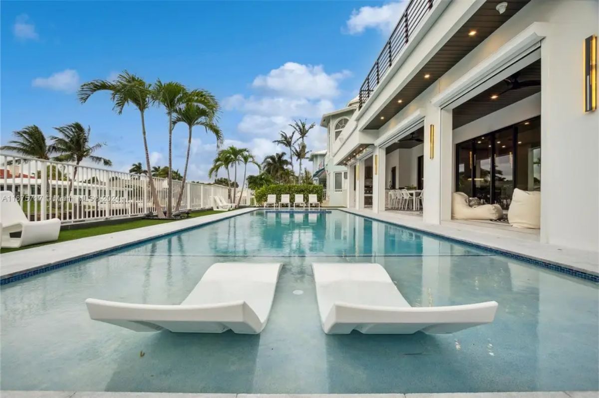 Lounge chairs partially submerged in a luxurious backyard pool create a resort-like atmosphere. 