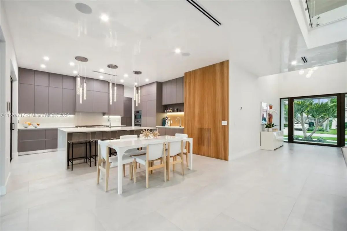Spacious open-concept kitchen and dining area featuring a white dining table and wood-accented walls. 