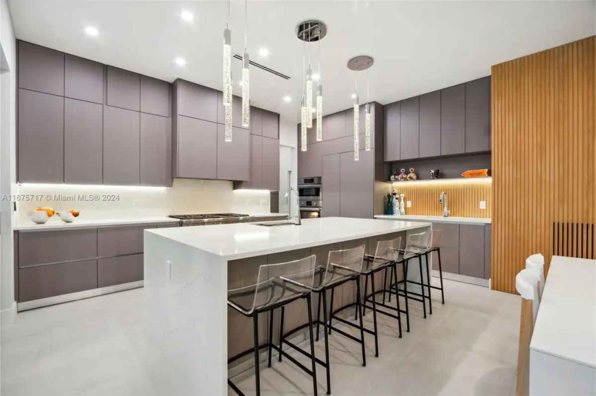 Contemporary kitchen with a large island, high-end appliances, and stylish hanging light fixtures. 