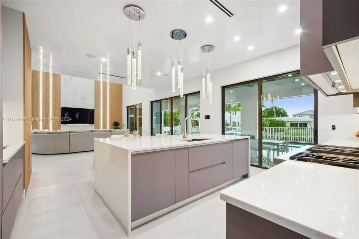 Bright and airy kitchen with a central island, floor-to-ceiling cabinets, and sliding glass doors leading to the patio. 