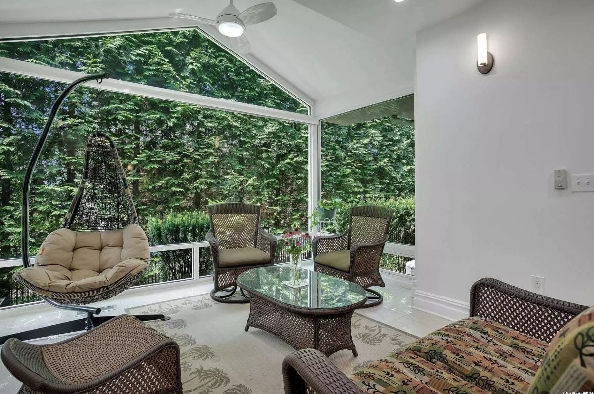 Glass-enclosed sunroom with a ceiling fan and outdoor seating.
