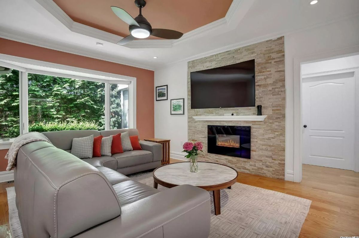 Large living room with a stone fireplace and mounted television.
