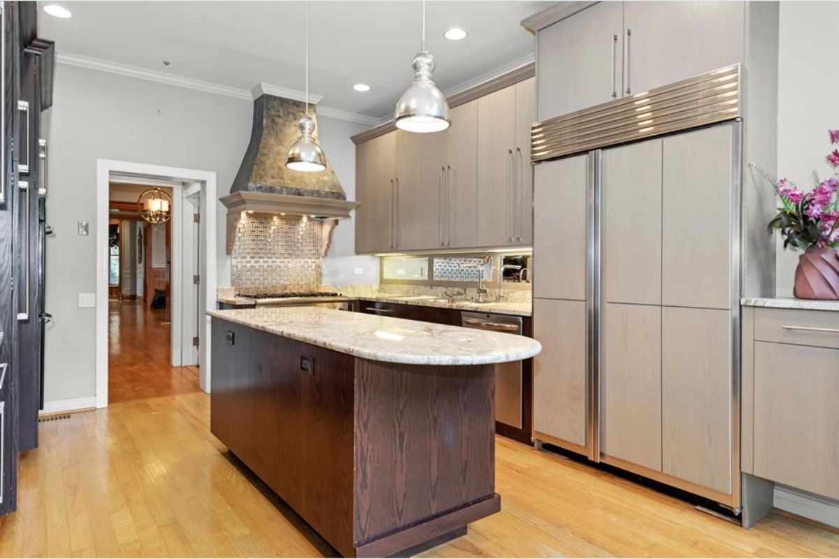 Neutral cabinetry and stainless steel appliances contrast with a dark wood island.