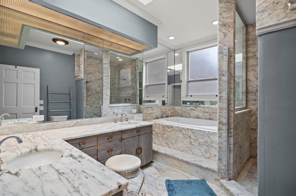 Marble surfaces extend throughout the space, covering countertops, walls, and the built-in spa tub.