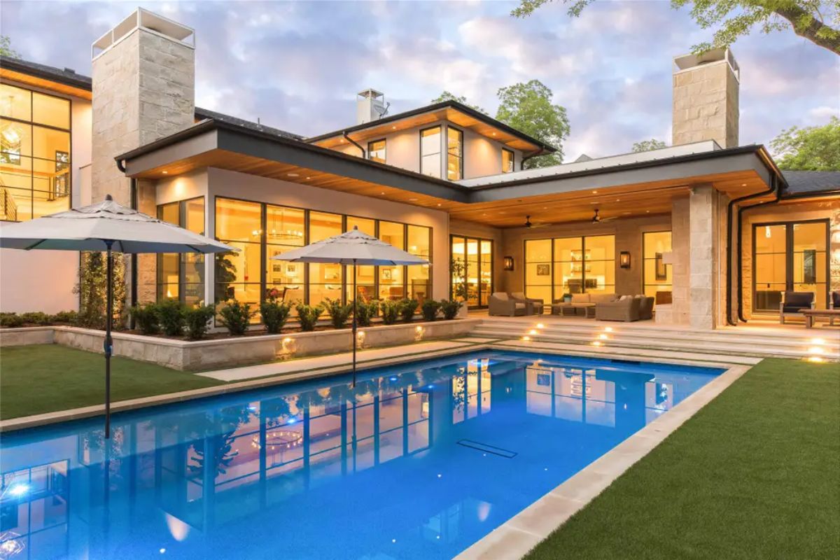 Stunning backyard featuring a modern swimming pool, expansive patio, and floor-to-ceiling glass doors leading inside. 