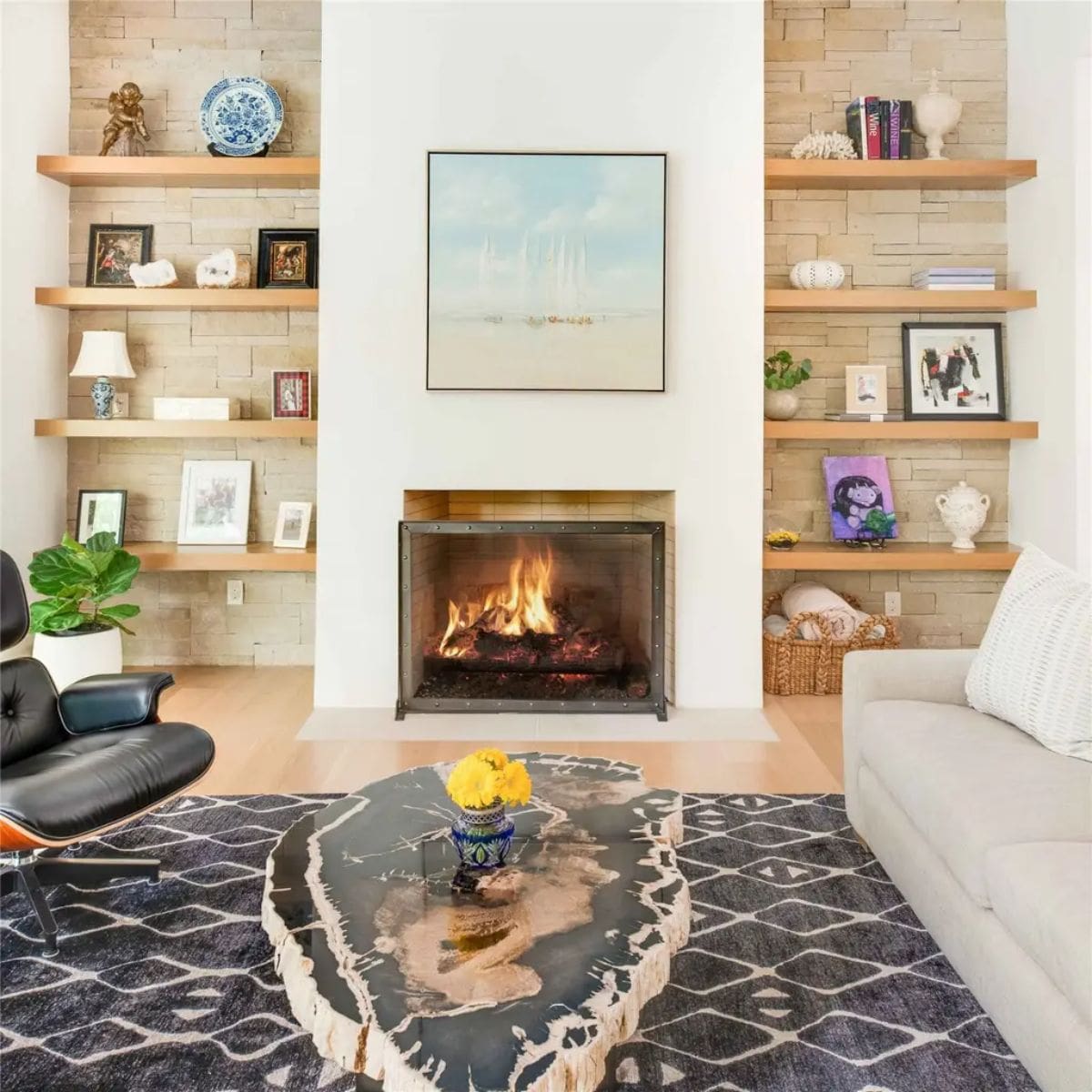 Cozy sitting area with a fireplace, built-in wooden shelves, and a unique petrified wood coffee table. 
