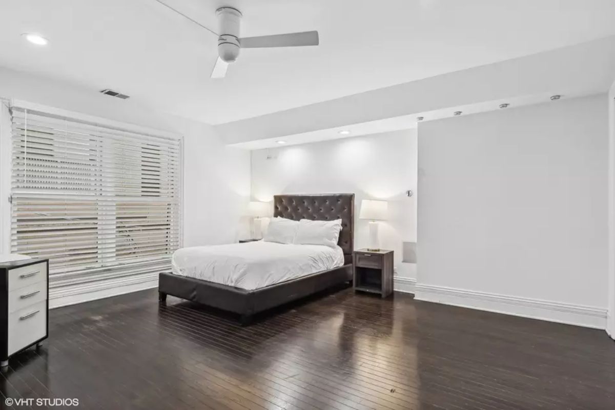 A tufted headboard stands against a bright white accent wall.