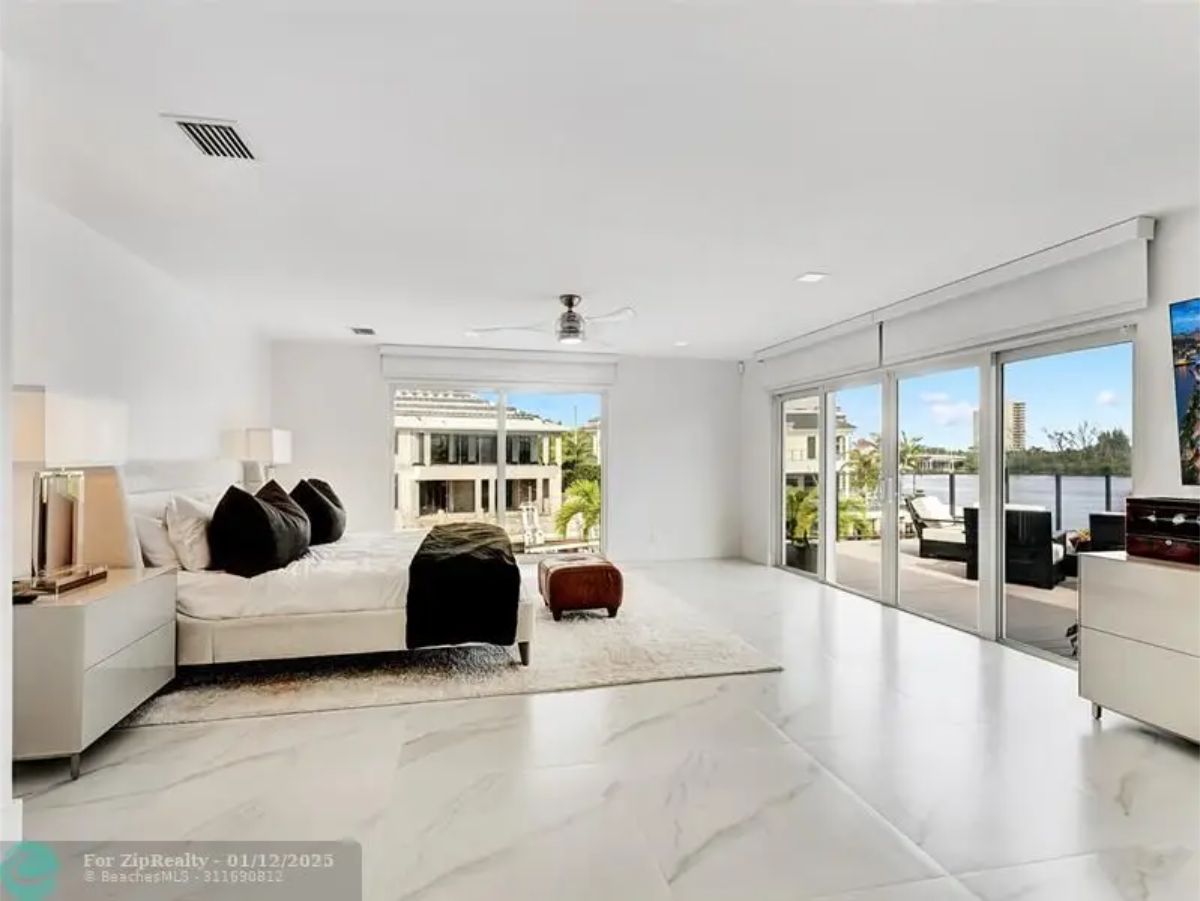 Expansive bedroom with large windows, a private balcony, and a view of the water. 