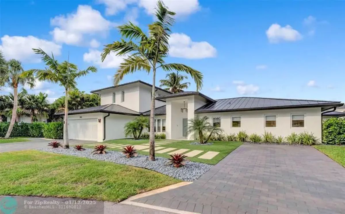 Modern home exterior with sleek architecture, tropical landscaping, and a spacious driveway. 