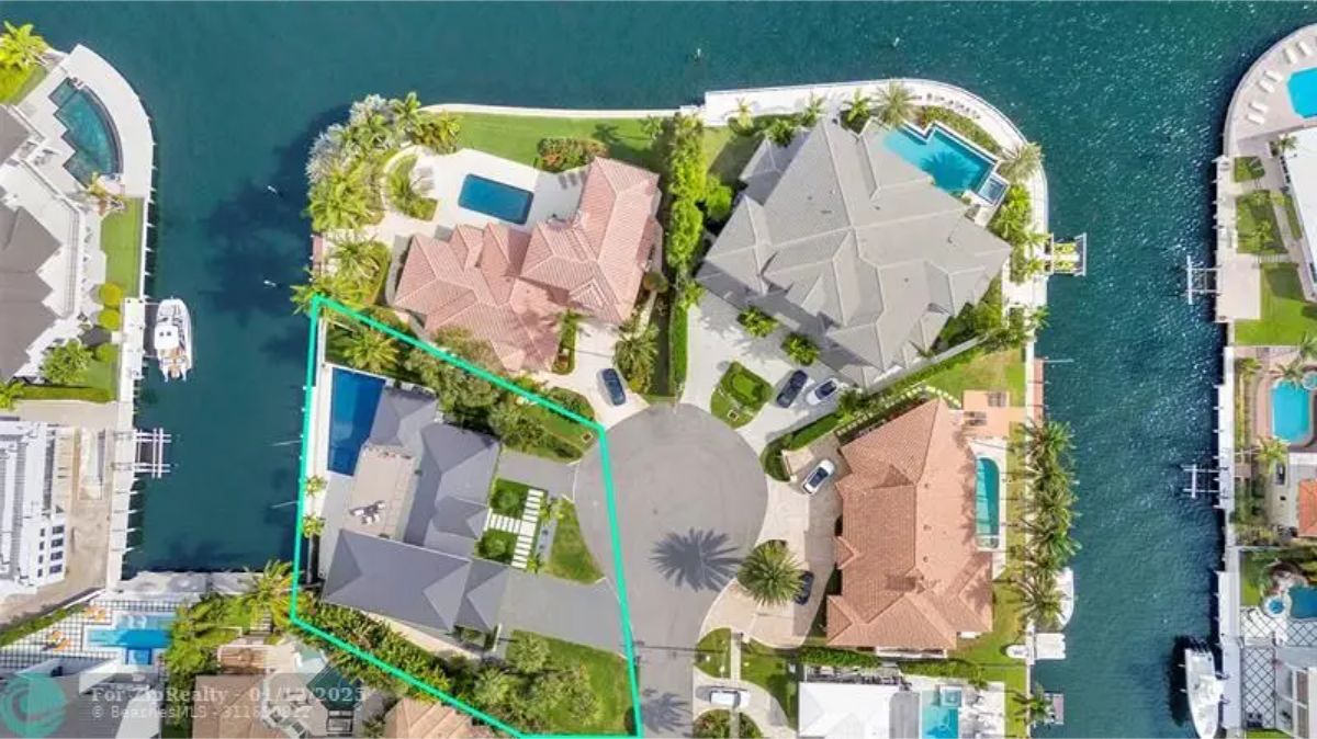 Aerial view of a luxurious cul-de-sac neighborhood, with a waterfront home outlined in green. 