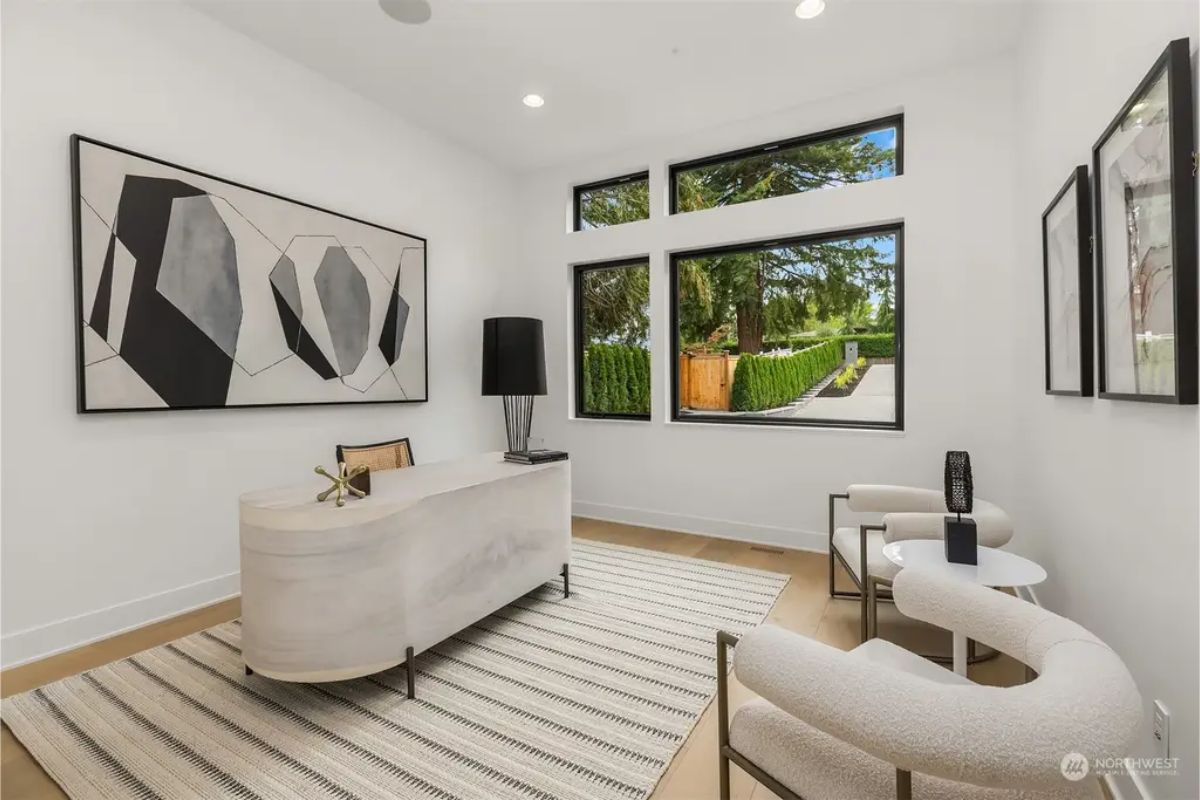 Stylish home office with geometric artwork, contemporary furniture, and large windows offering natural light. 
