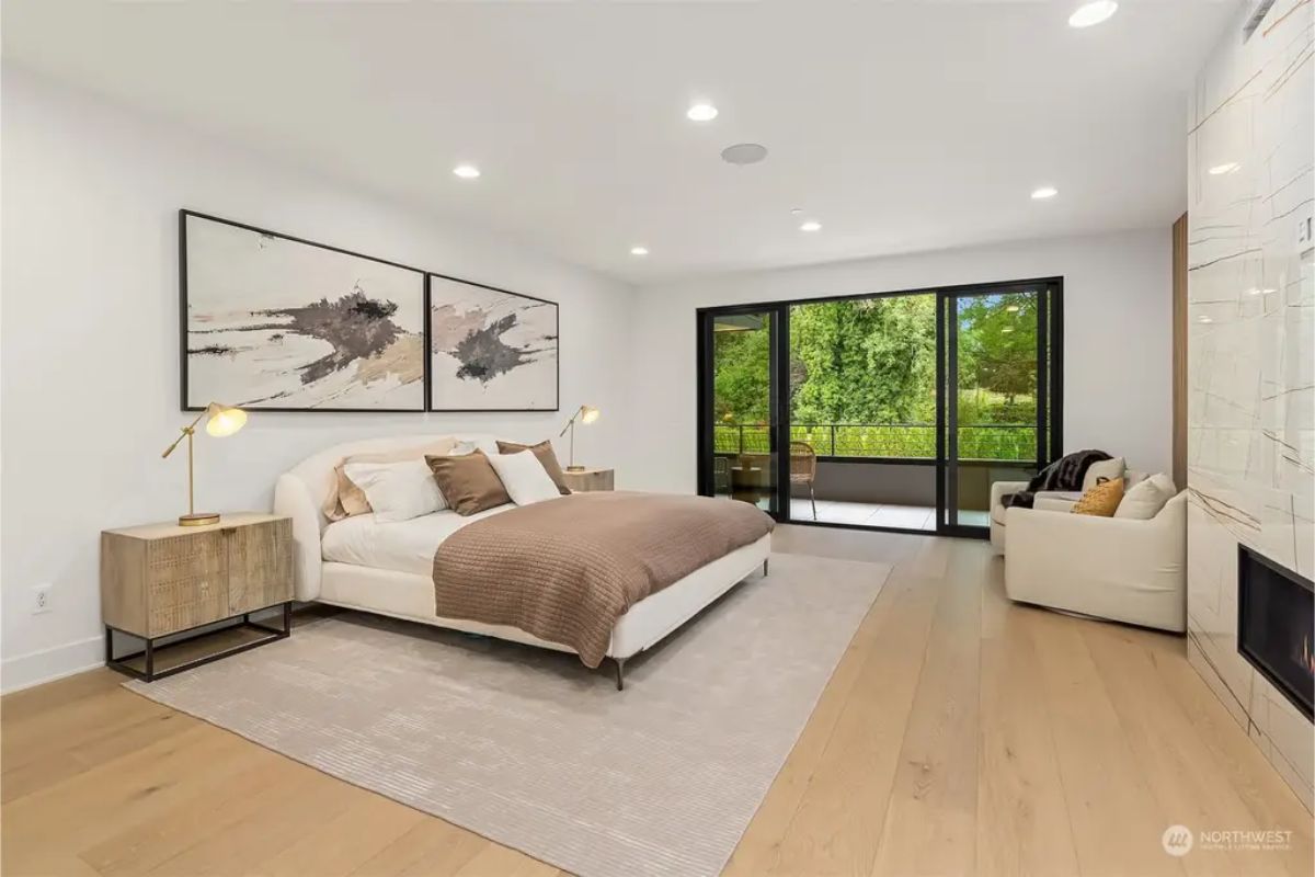 Spacious bedroom with a modern design, large glass doors leading to a balcony, and neutral tones. 