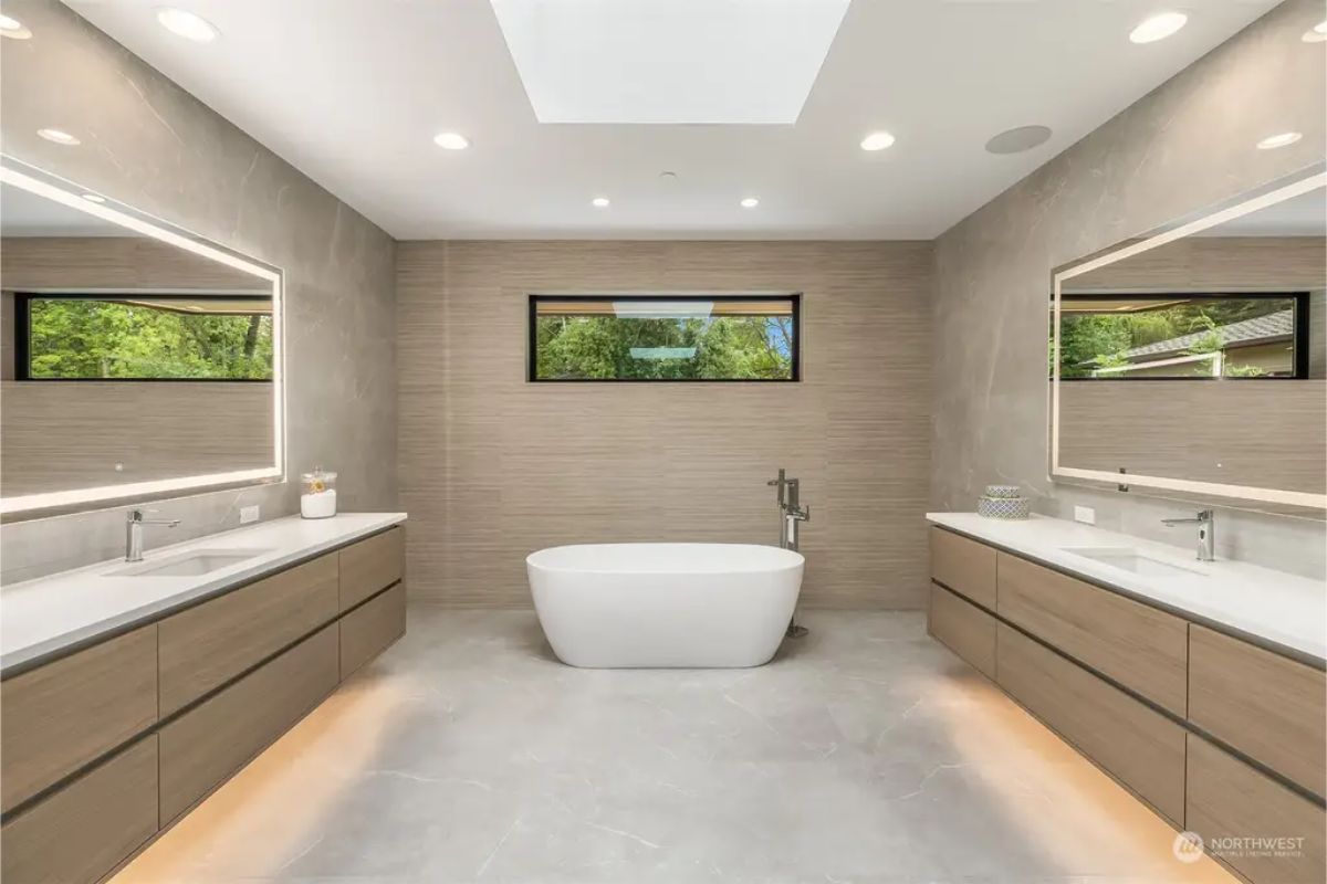 Elegant bathroom with dual vanities, a freestanding bathtub, and a sleek, neutral color palette. 
