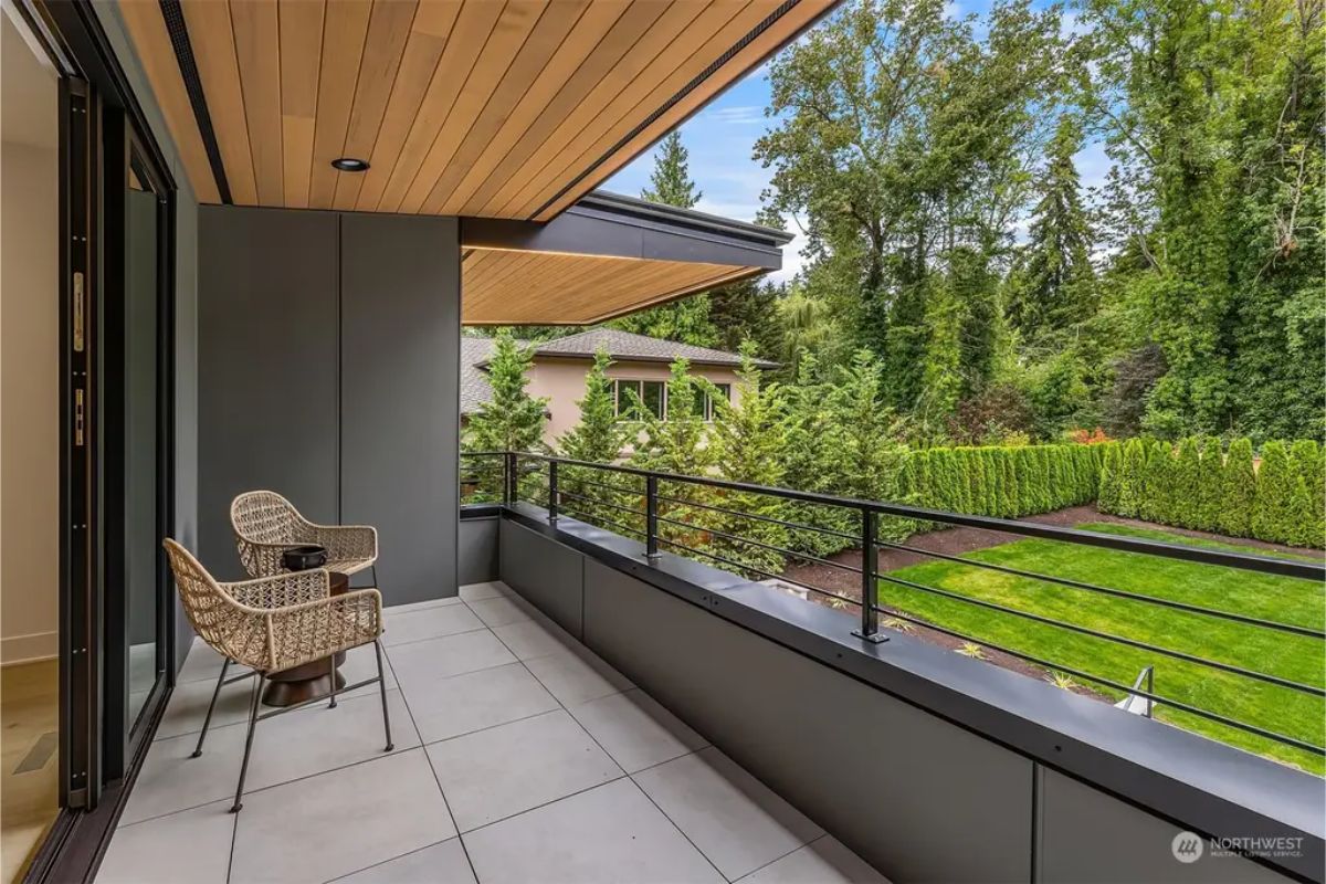 Private balcony with wooden ceiling details, modern railing, and serene garden views. 