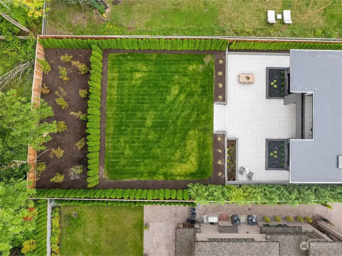 Aerial view of a landscaped backyard with manicured greenery, a patio, and modern design elements. 