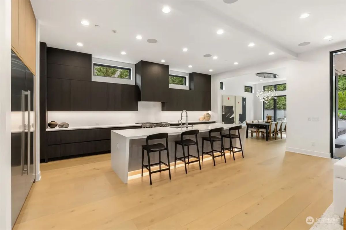Sleek kitchen with black and wood cabinetry, a large island with barstools, and high-end stainless steel appliances. 
