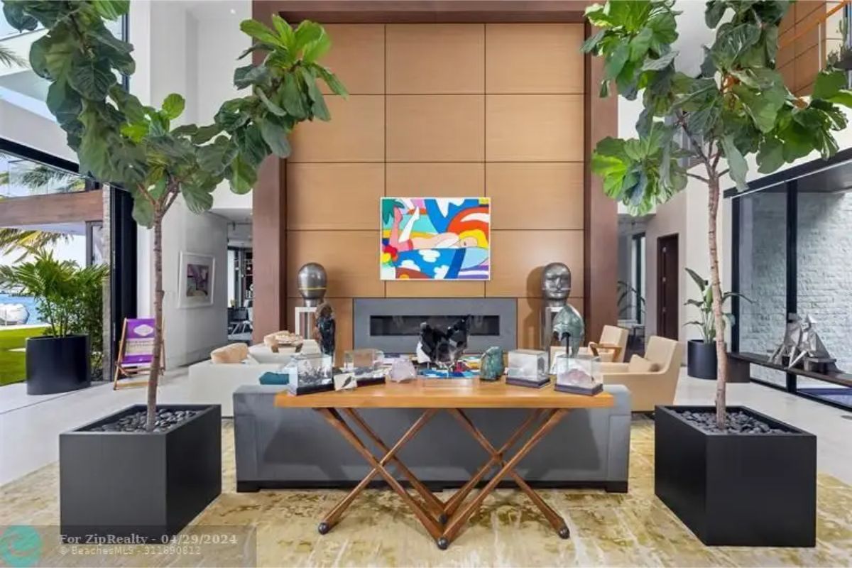 Close-up of the living room showcasing a wooden feature wall with colorful artwork, decorative sculptures, and potted trees. 
