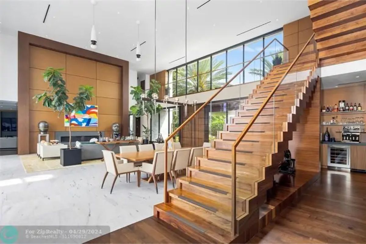 Wooden staircase leading to the upper floor beside a dining and living area. 