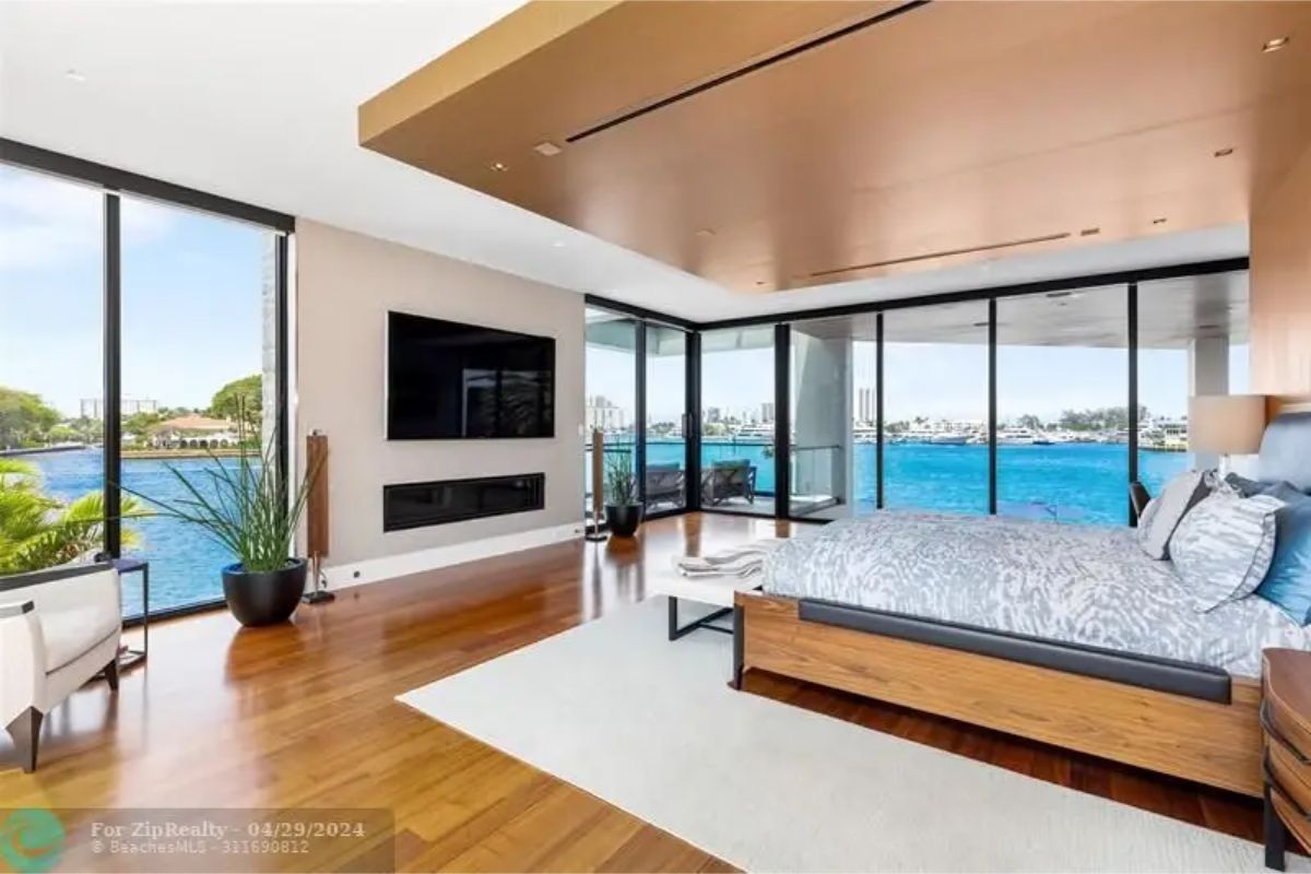 Bedroom with large windows offering a waterfront view and modern furnishings. 