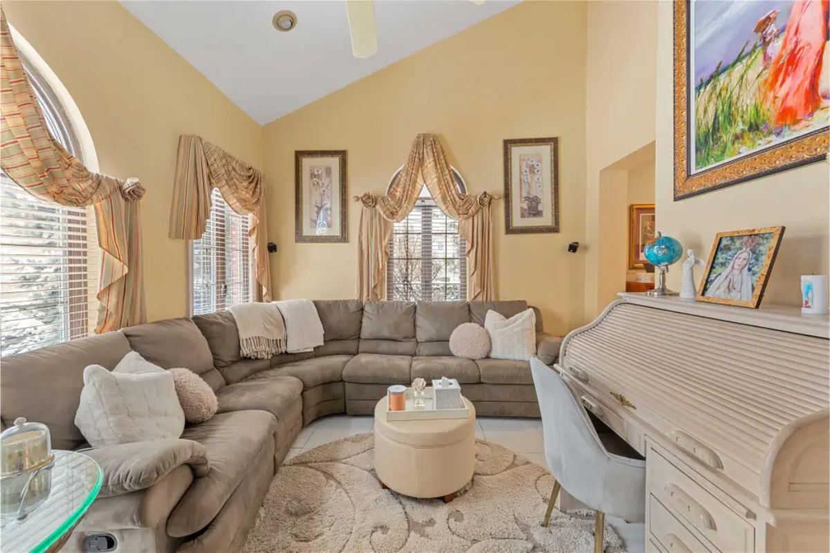 Large sectional sofa in neutral tones is arranged in a cozy living room with high vaulted ceilings.