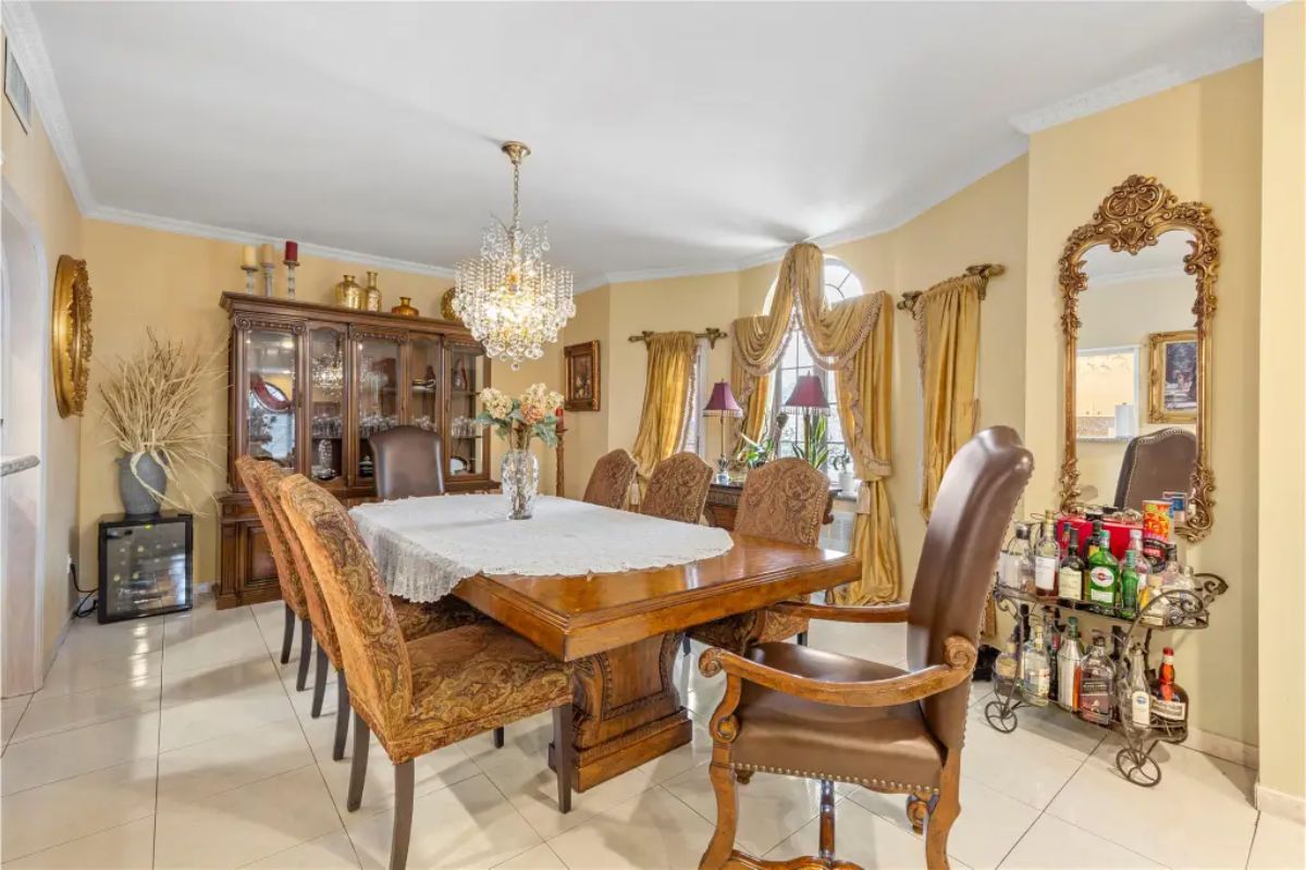 Formal dining room features a large wooden table surrounded by high-backed, upholstered chairs.