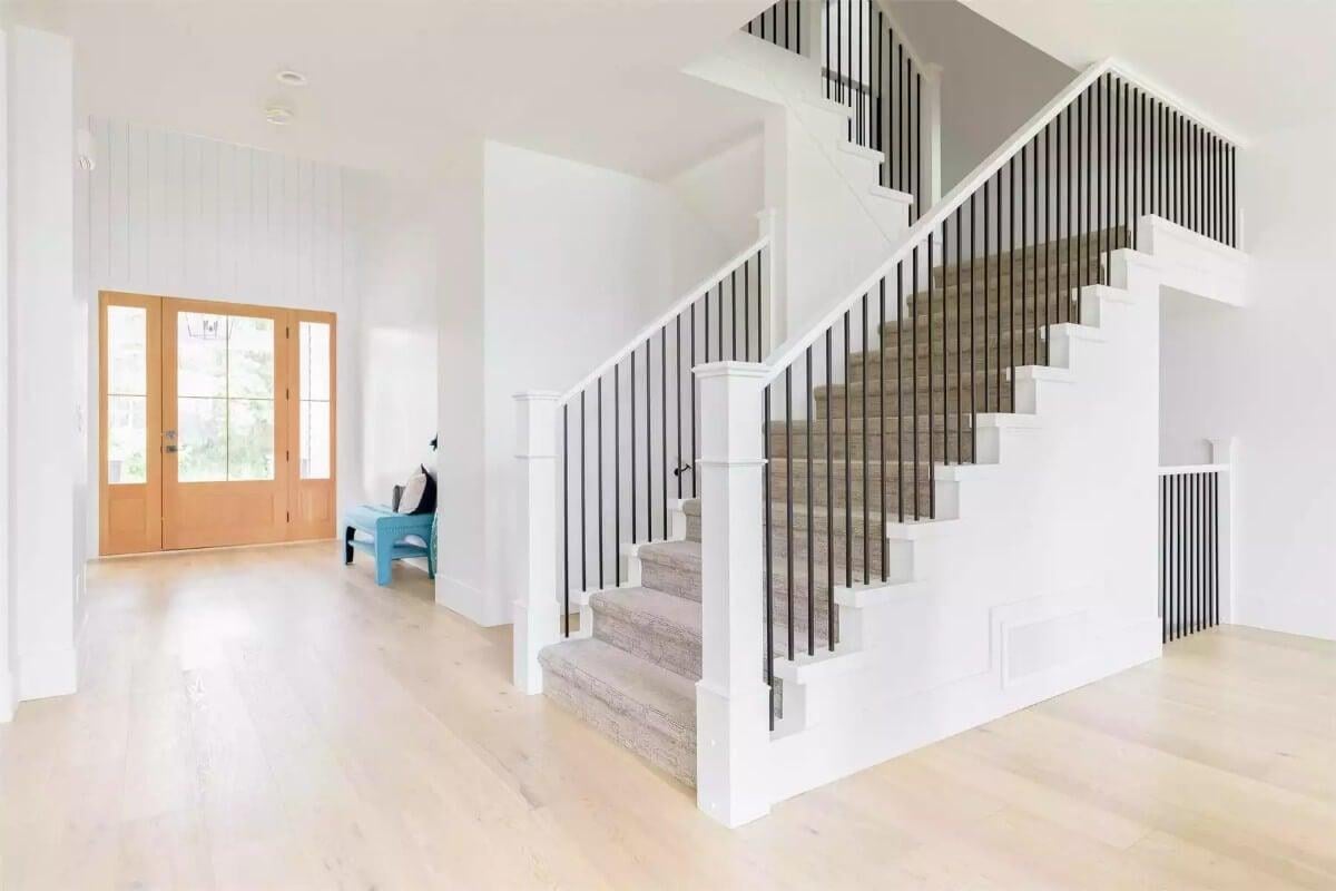 Ein heller Eingang mit einer eleganten Treppe und einladender warmer Akzente