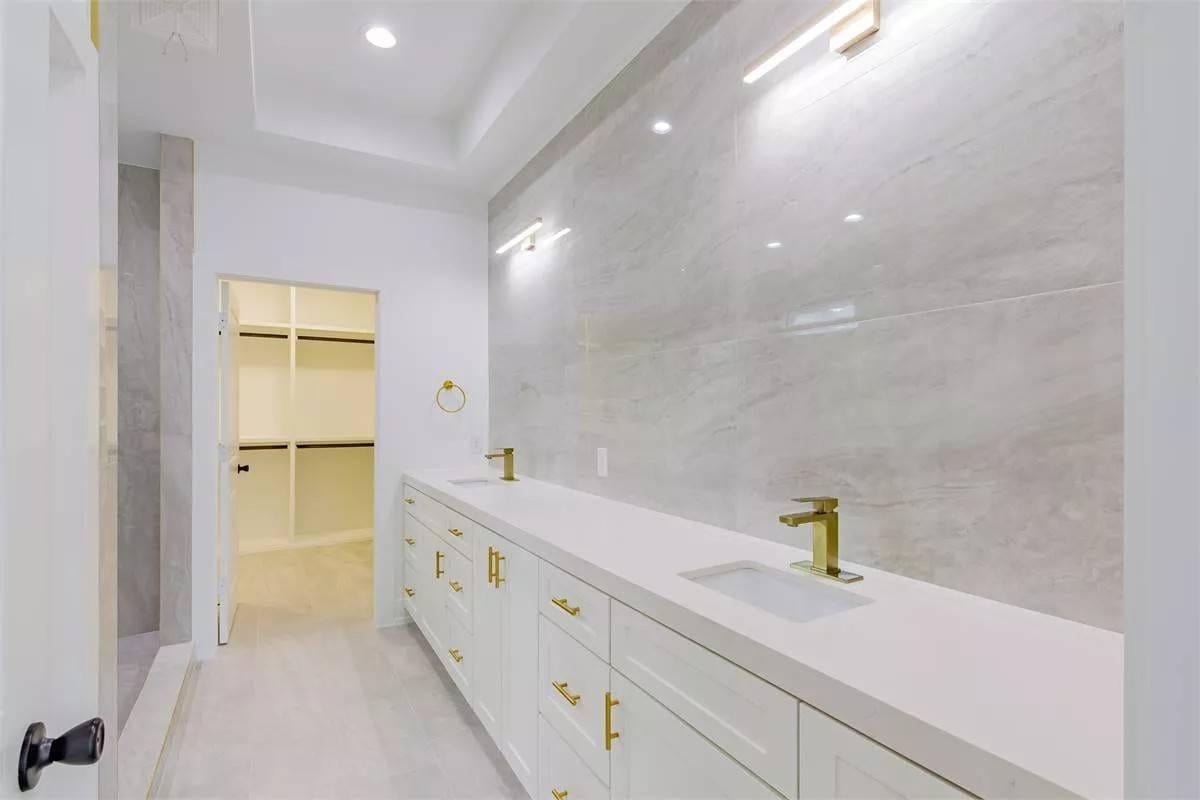 Admire the Sleek Wall-to-Wall Vanity with Gold Accents