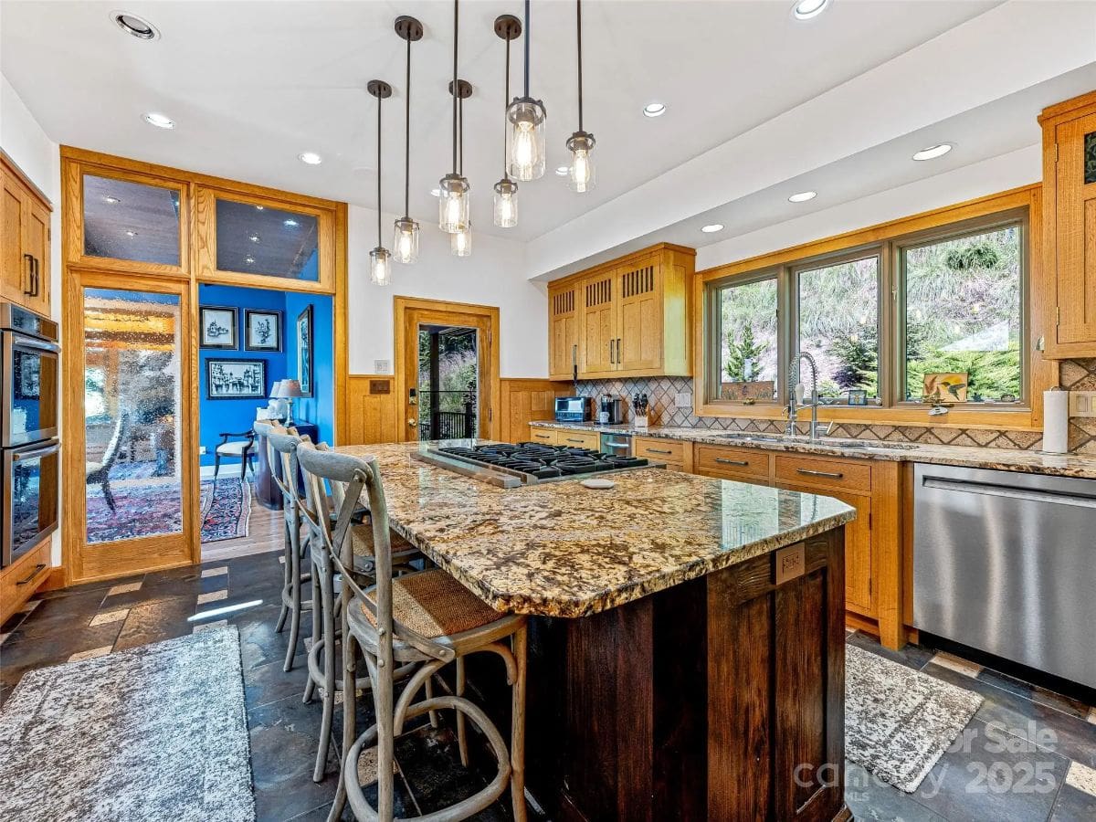 Kitchen features wood cabinetry, granite countertops, and a central island with bar seating.