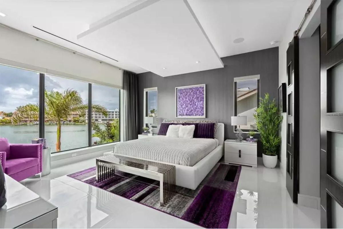 Floor-to-ceiling windows overlook palm trees and water.