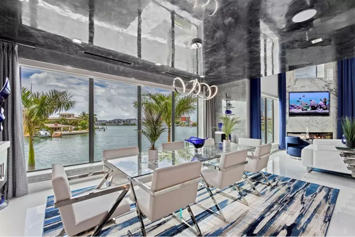 Glass dining table is surrounded by modern white chairs.