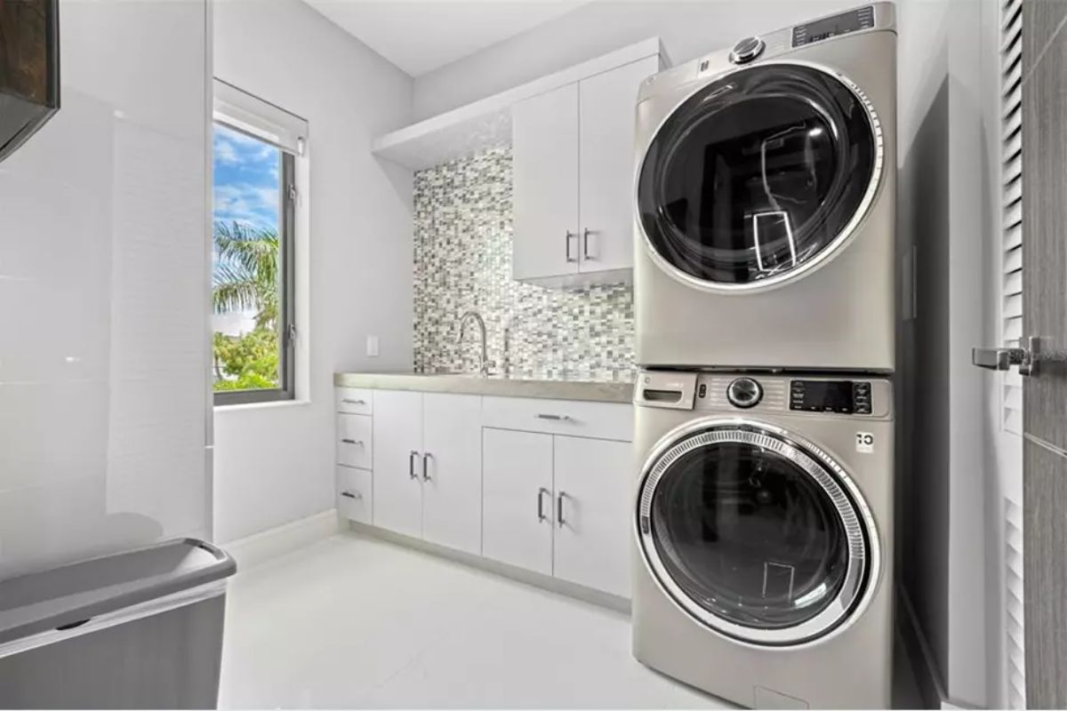 Compact laundry room with stacked stainless washer and dryer,