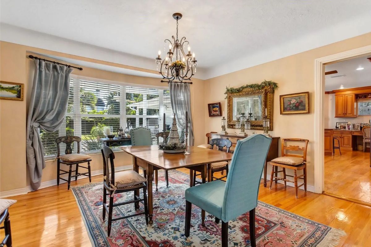Dining area centers around a wooden table with a mix of formal and casual chairs.