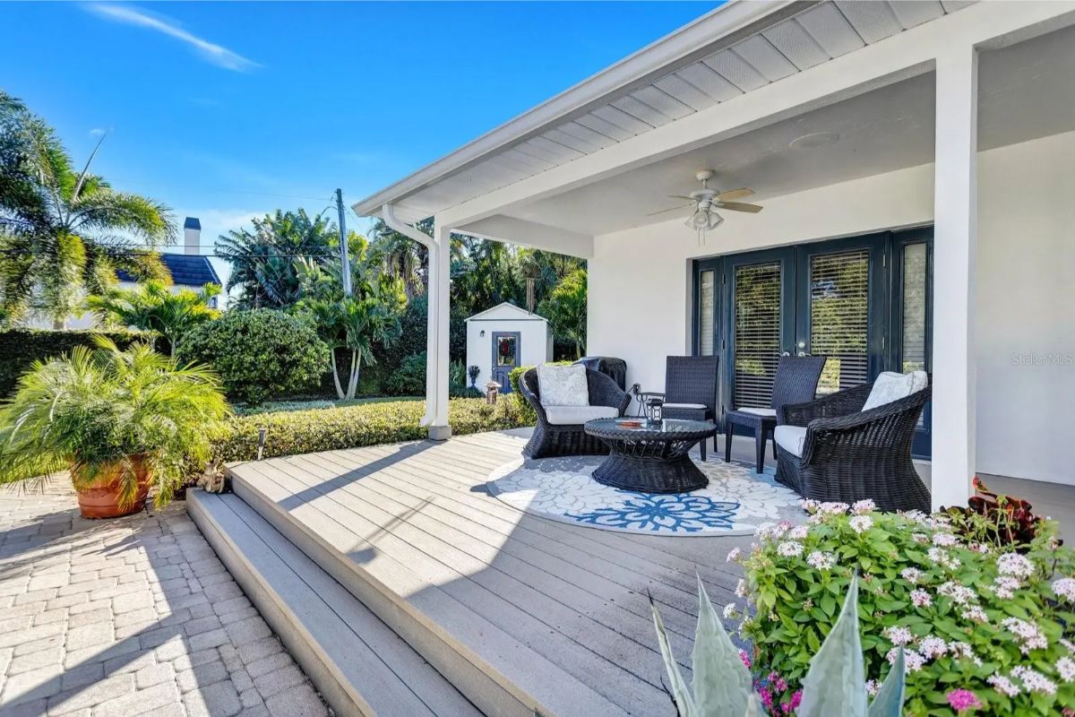 Back patio has a small deck area with wicker chairs and a ceiling fan overhead.