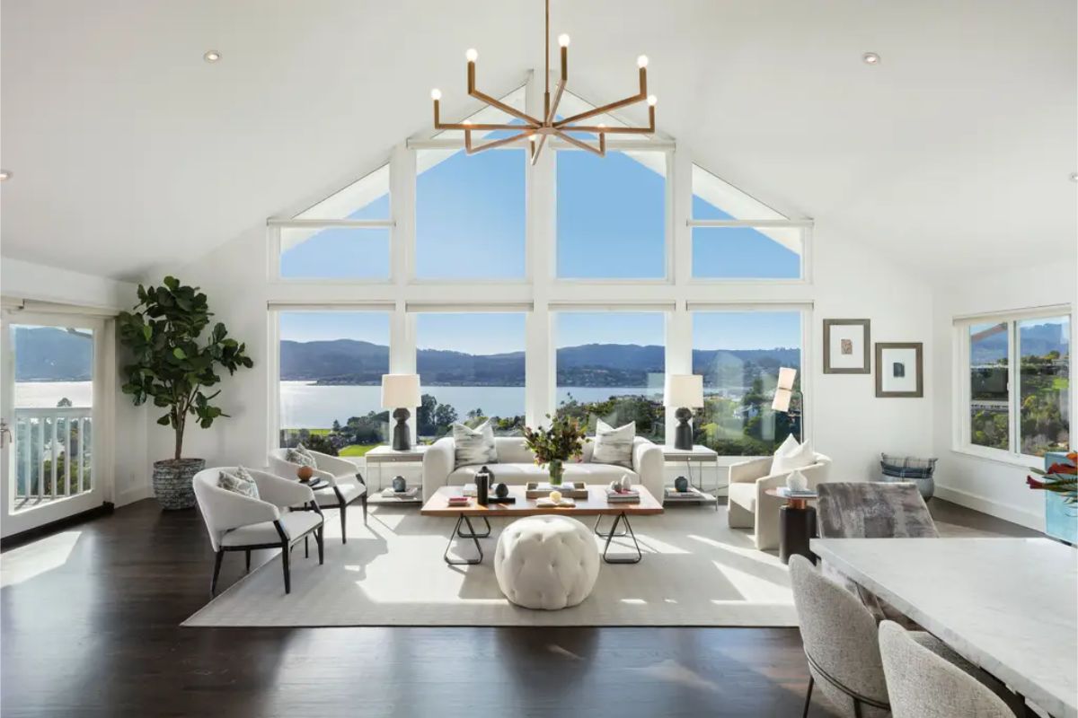 Spacious living room with vaulted ceilings, floor-to-ceiling windows, and a breathtaking view of the water. 