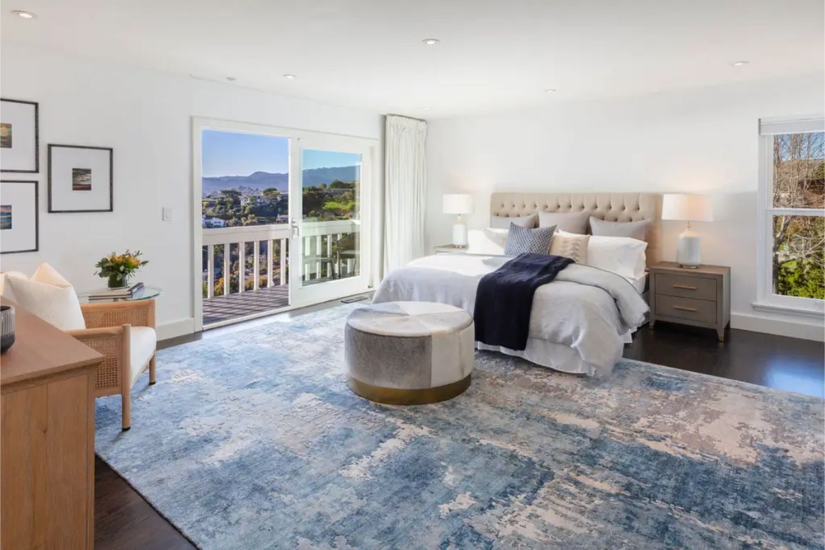 Expansive primary bedroom with a private balcony, plush furnishings, and a serene color palette. 