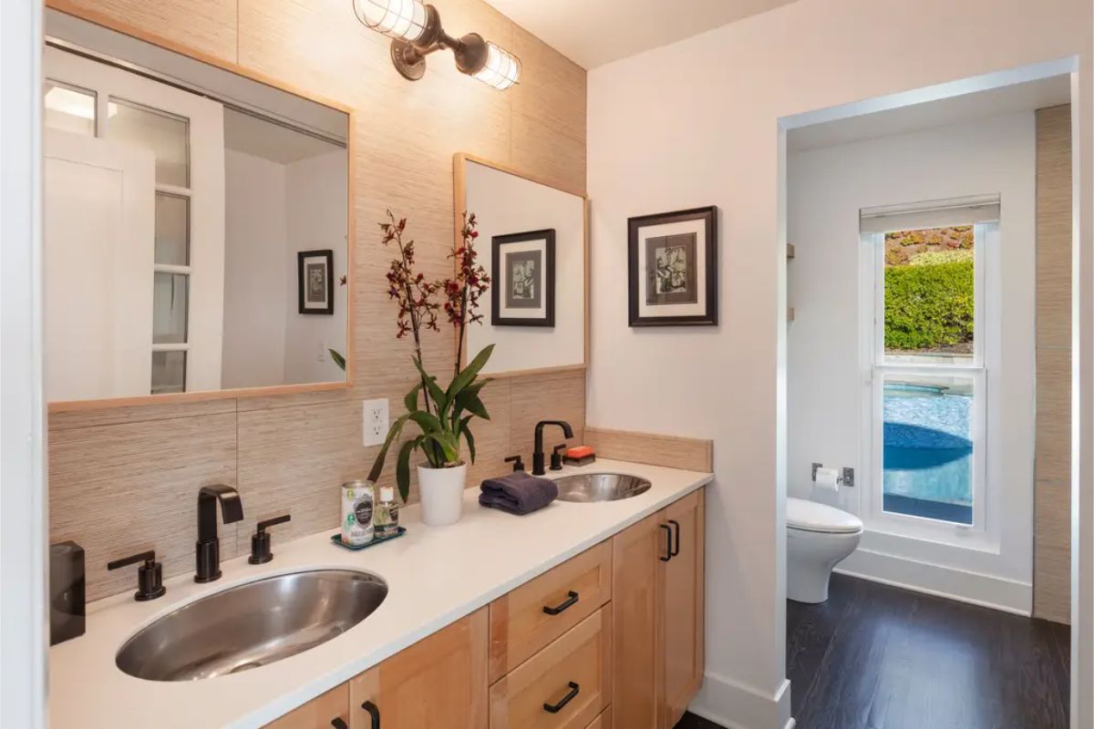 Stylish bathroom with a double vanity, wood cabinetry, and a modern design featuring black fixtures. 