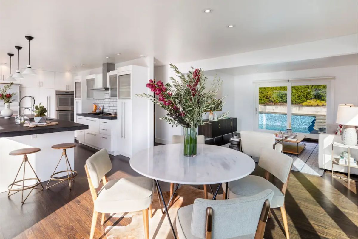 Contemporary kitchen and breakfast nook with sleek white cabinetry, dark countertops, and a cozy seating area. 