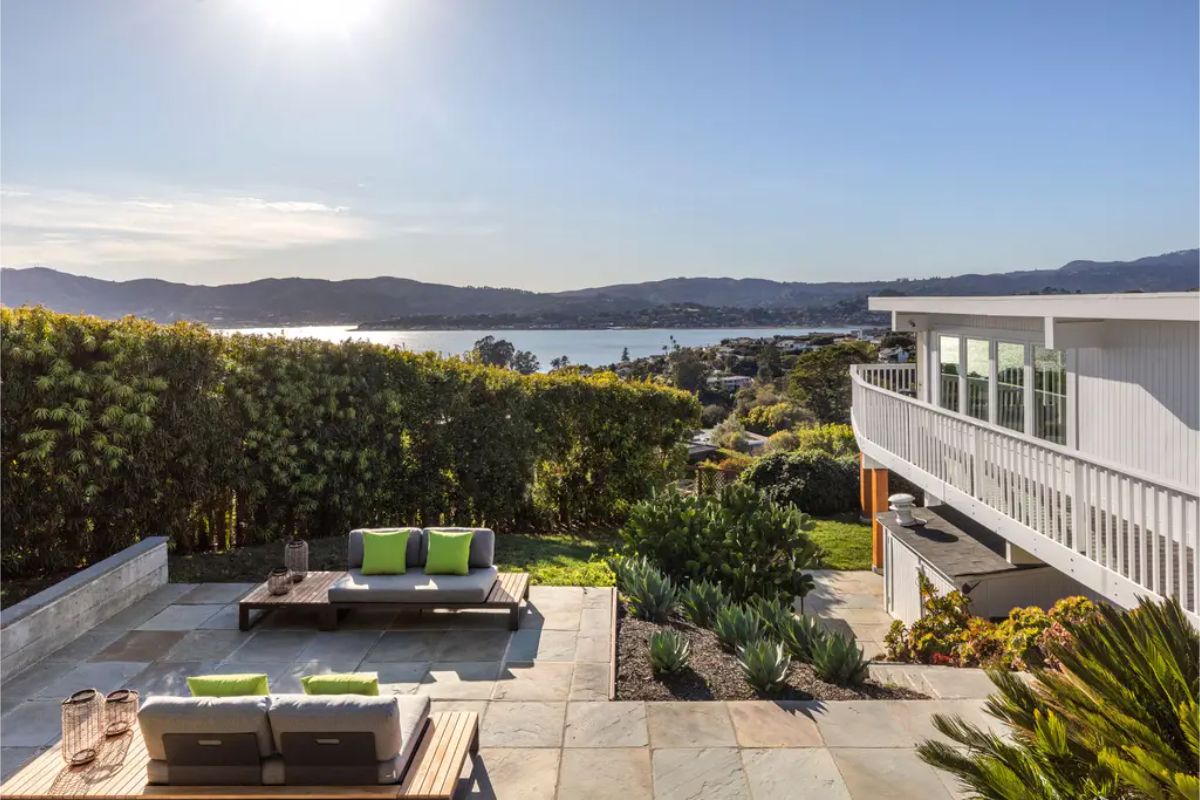 Beautifully landscaped terrace with lush greenery, outdoor lounge furniture, and a stunning waterfront backdrop. 
